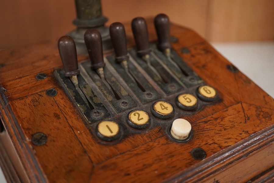 An early 20th century mahogany cased telephone, possibly by Ericsson, with handset on decorative cradle and five switchboard selector levers, stamped ‘Patent’ to front of the case, and with paper label underneath reading